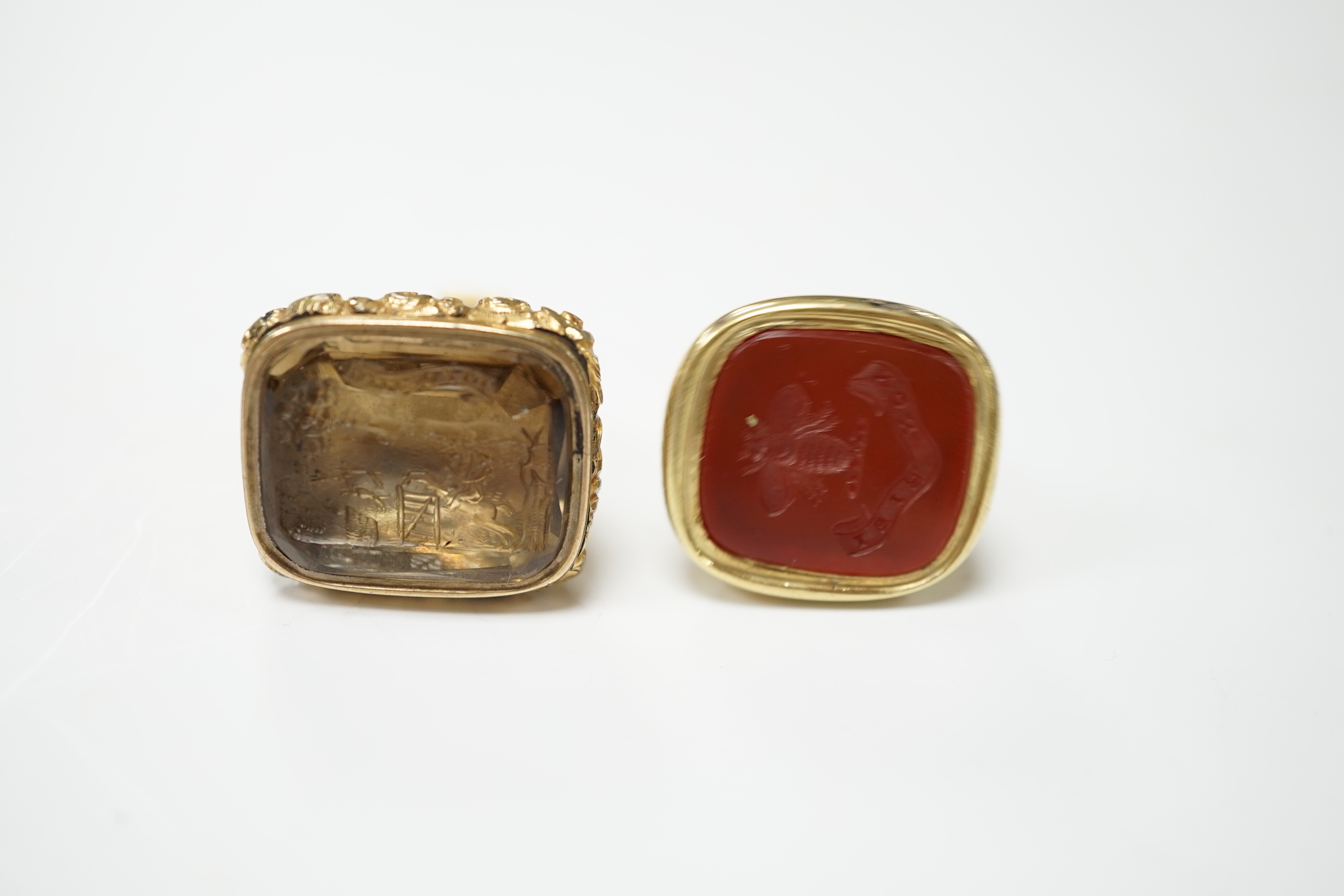 Two 19th century yellow metal overlaid fob seals, the largest 32mm with inset citrine carved with ornate crest and inscribed 'Joy of Life', the other with inset carnelian craved with bee and inscribed 'Non Sibi'.